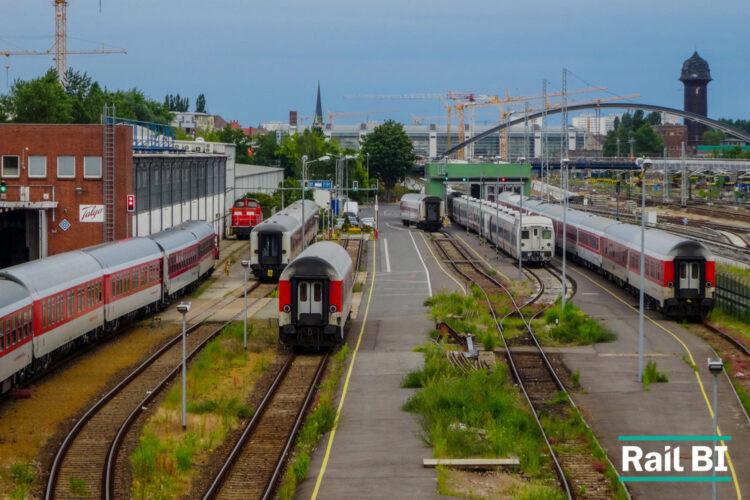 Passenger trains and multiple rail tracks at a busy urban rail yard, showing the complexity of infrastructure planning across a live rail network.